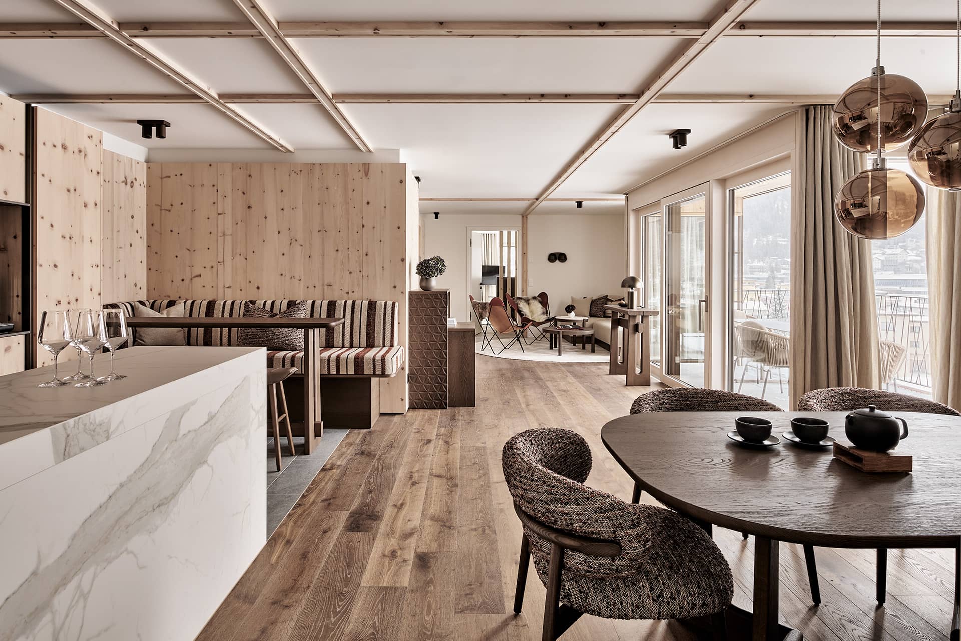 Offener Wohn- und Essbereich des Penthouses mit Küche, Sitzbank und Blick durch bodentiefe Fenster