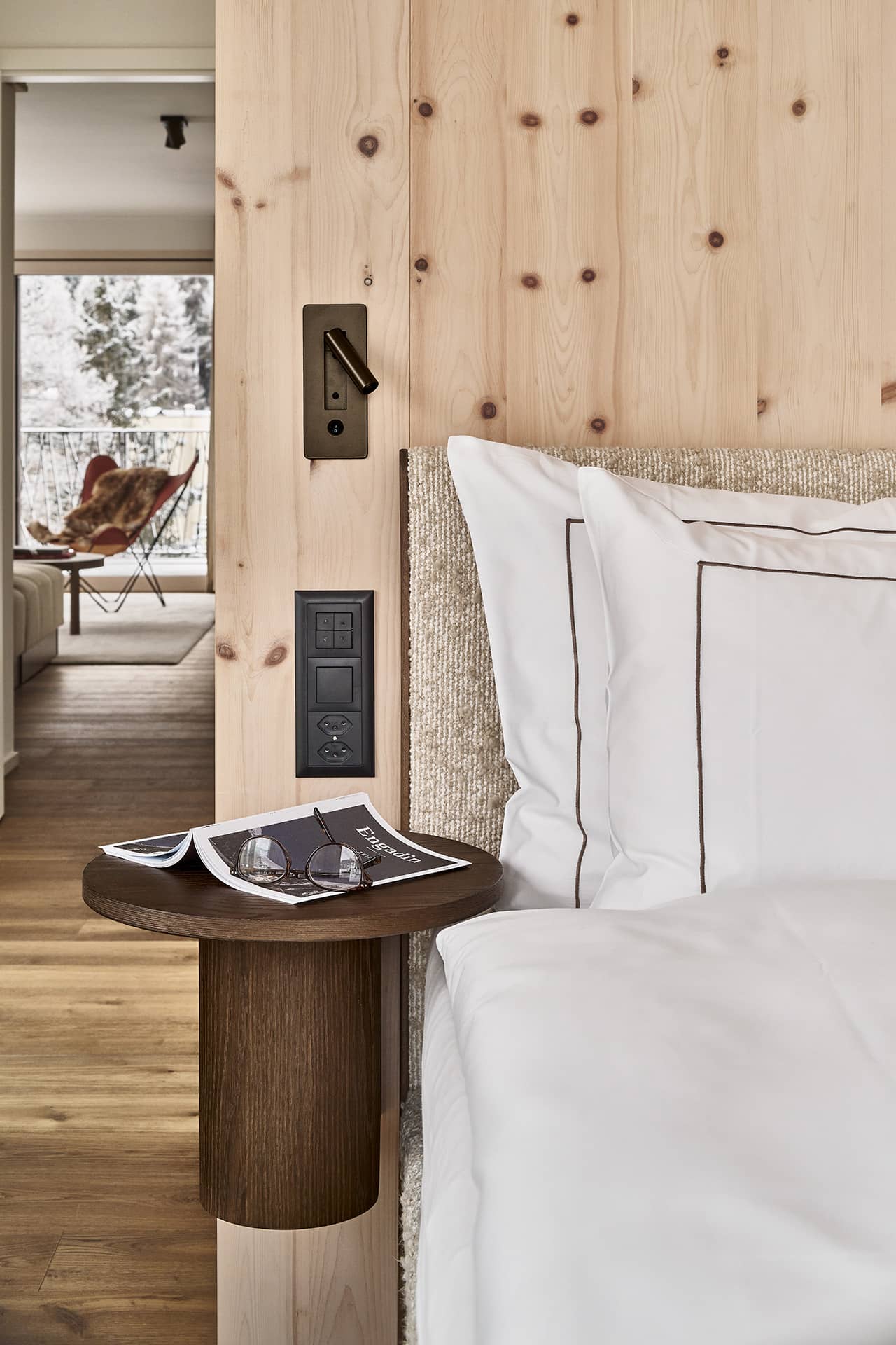 Detailansicht des Schlafbereichs mit Nachttisch, Leselampe und Holzwand