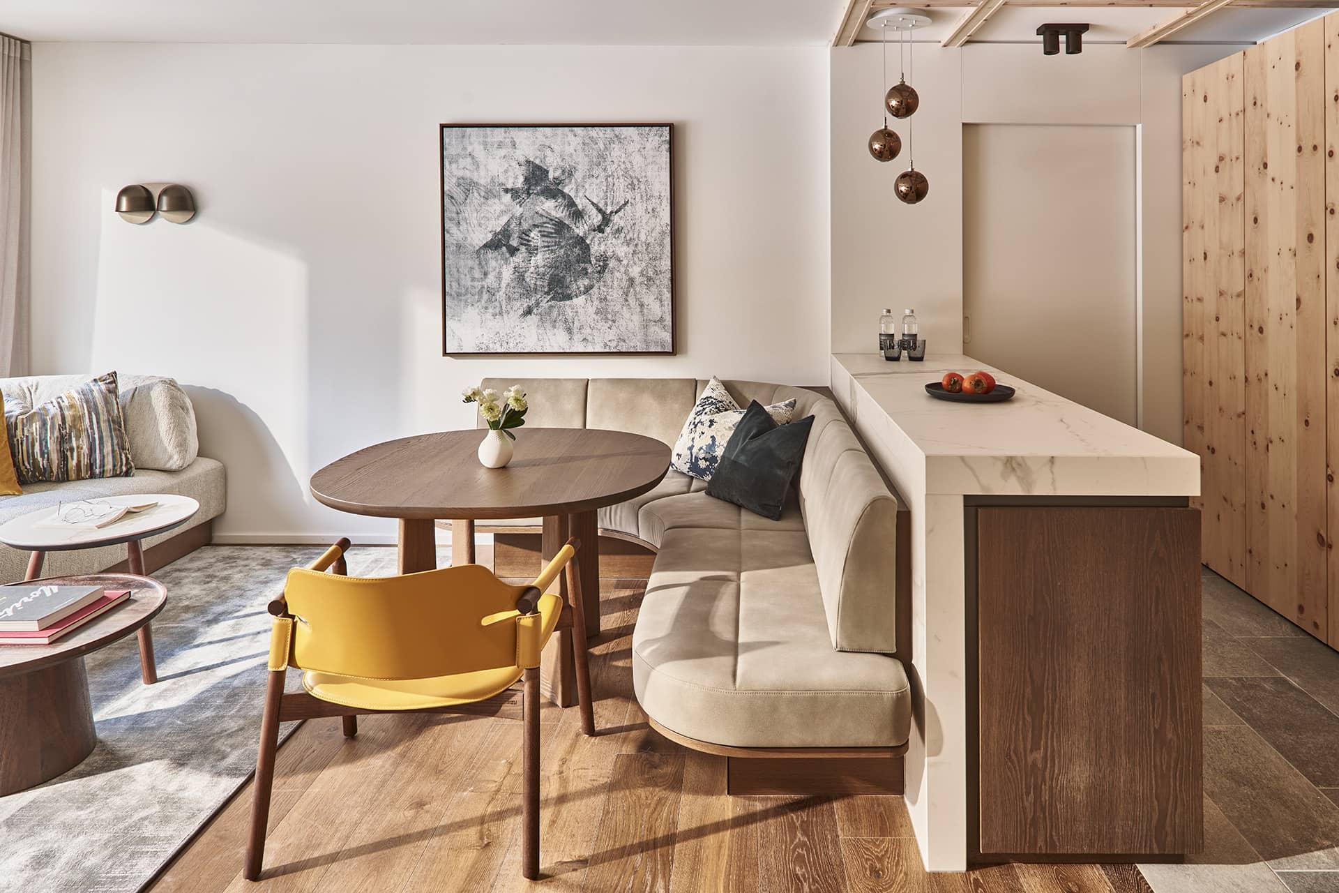 Offener Wohn- und Essbereich der Premium Suite mit Sitzbank, rundem Tisch und moderner Küchenzeile