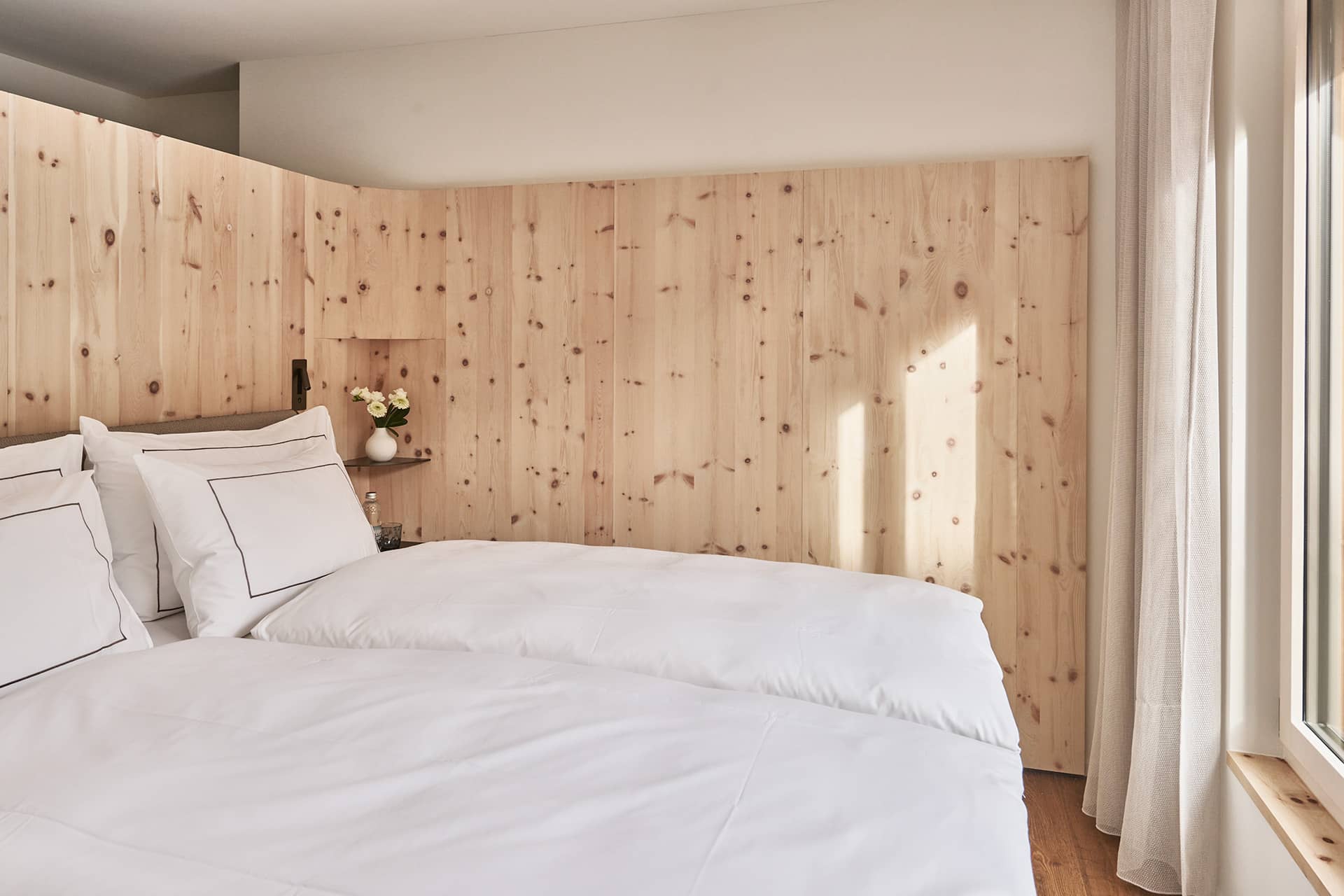 Schlafbereich der Premium Suite mit Holzwand und klarer, ruhiger Gestaltung