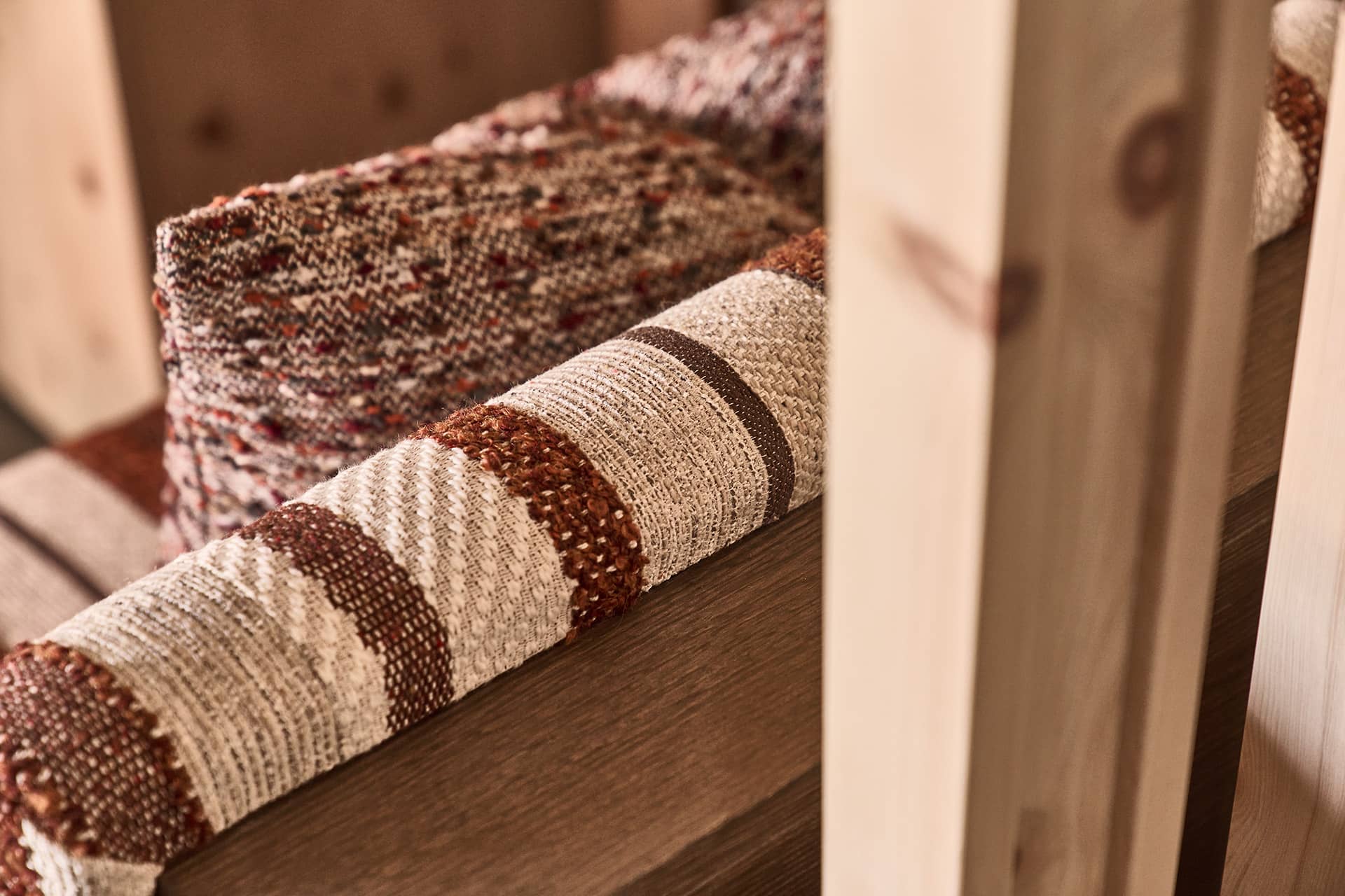 Detail der gepolsterten Sitzbank mit strukturierter Stoffoberfläche und Holzrahmen