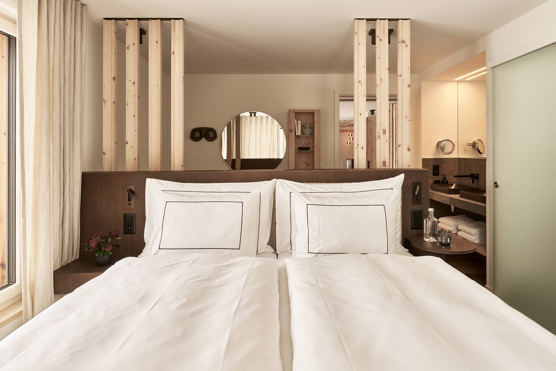 Schlafzimmer der Residence 2 mit Doppelbett, Holzdetails und offenem Badbereich