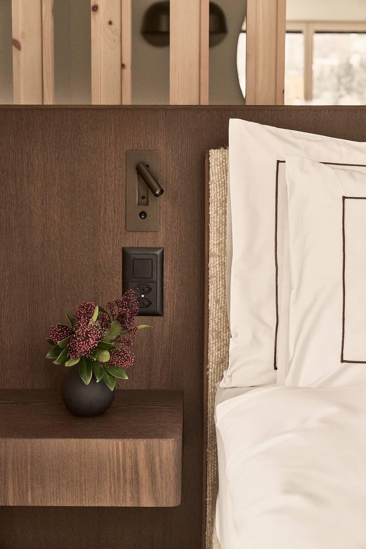 Detailansicht des Bettes mit Holzrückwand, Leselampe und Nachttisch