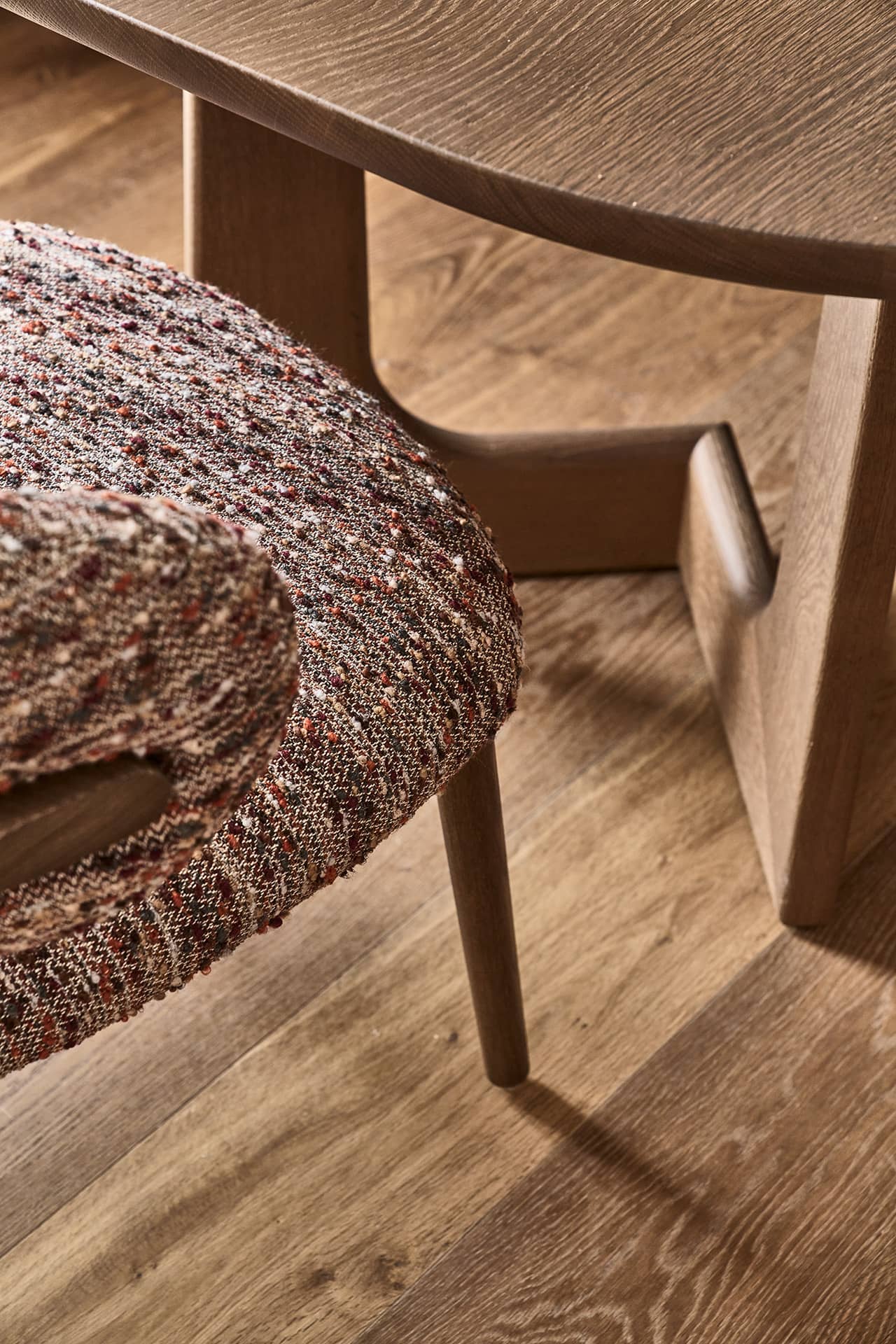 Detailansicht des Esstisches mit gepolstertem Stuhl und Holzfuß