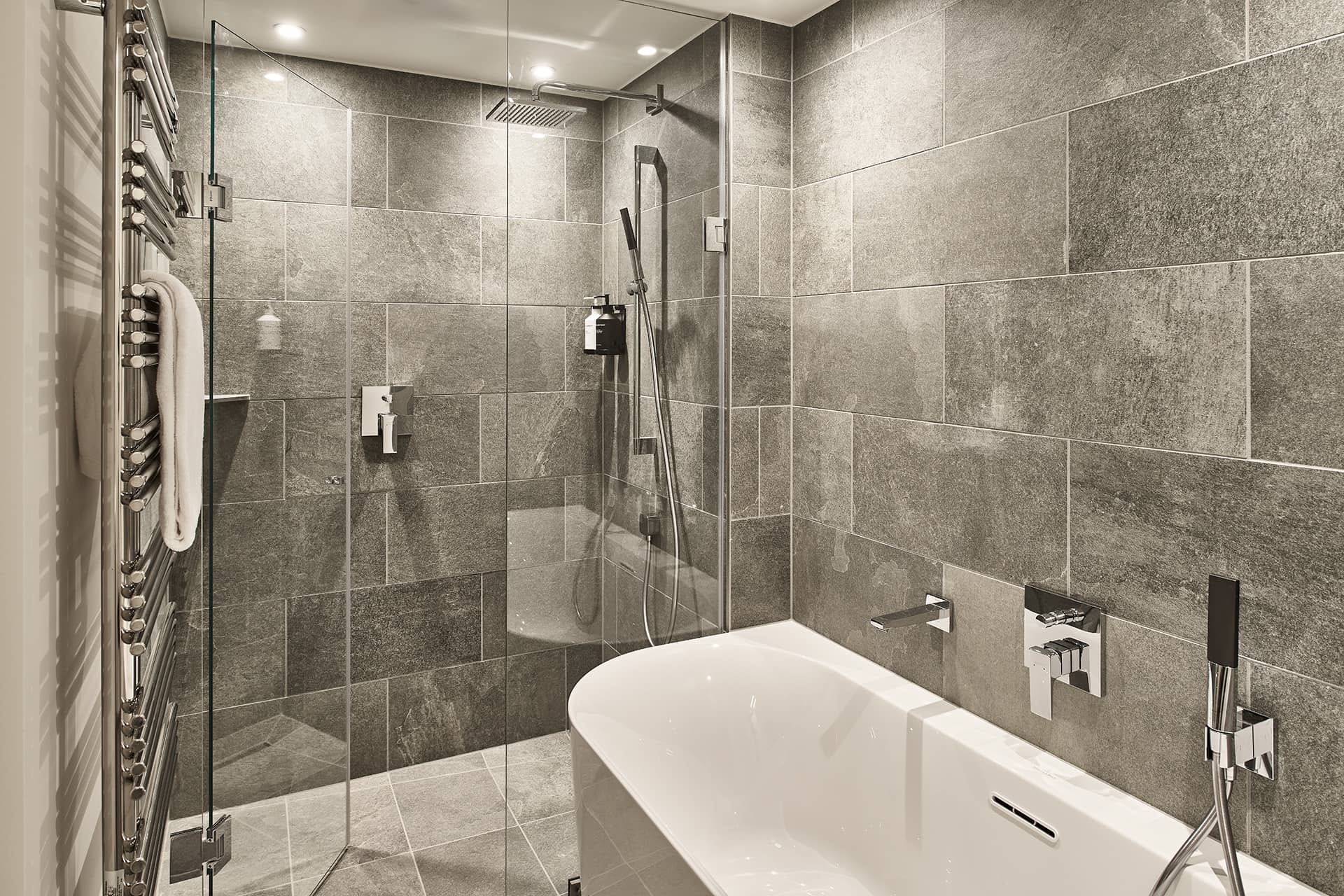 Detailansicht der Dusche mit Natursteinfliesen und Regendusche