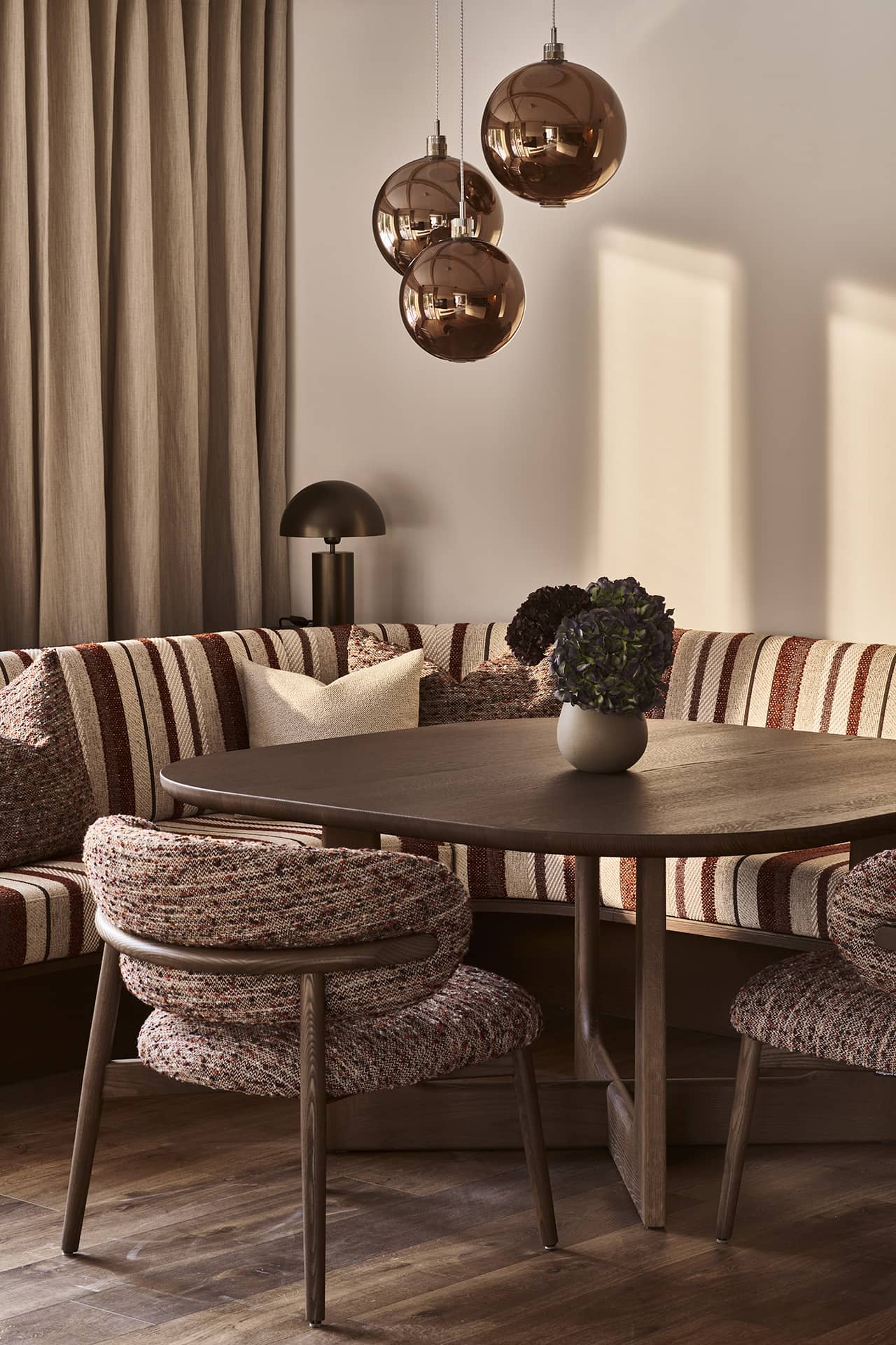 Detailansicht des Essbereichs mit Tisch, Polsterstühlen und Pendelleuchten