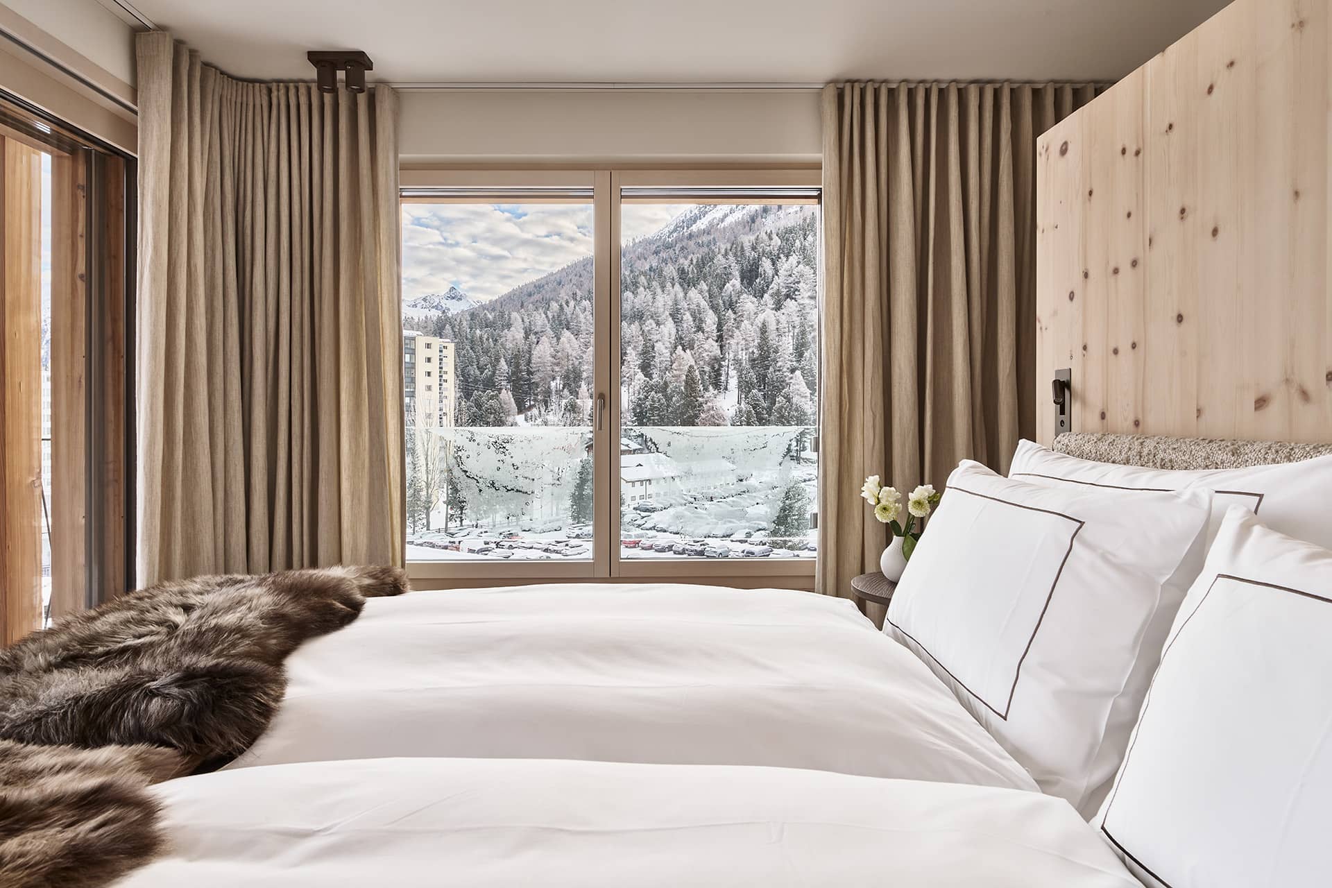 Schlafbereich der Residence 3 mit Blick aus dem Bett auf die verschneite Landschaft