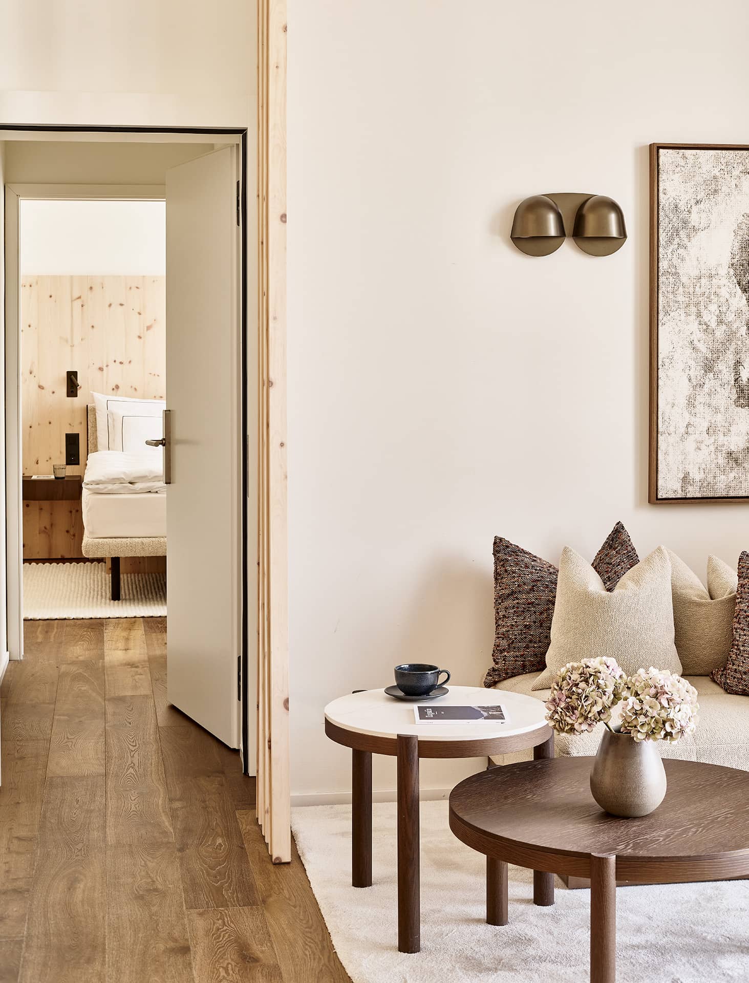 Gemütliche Sitzecke im Masterpenthouse mit Designmöbeln, warmen Naturtönen und Blick in das angrenzende Schlafzimmer