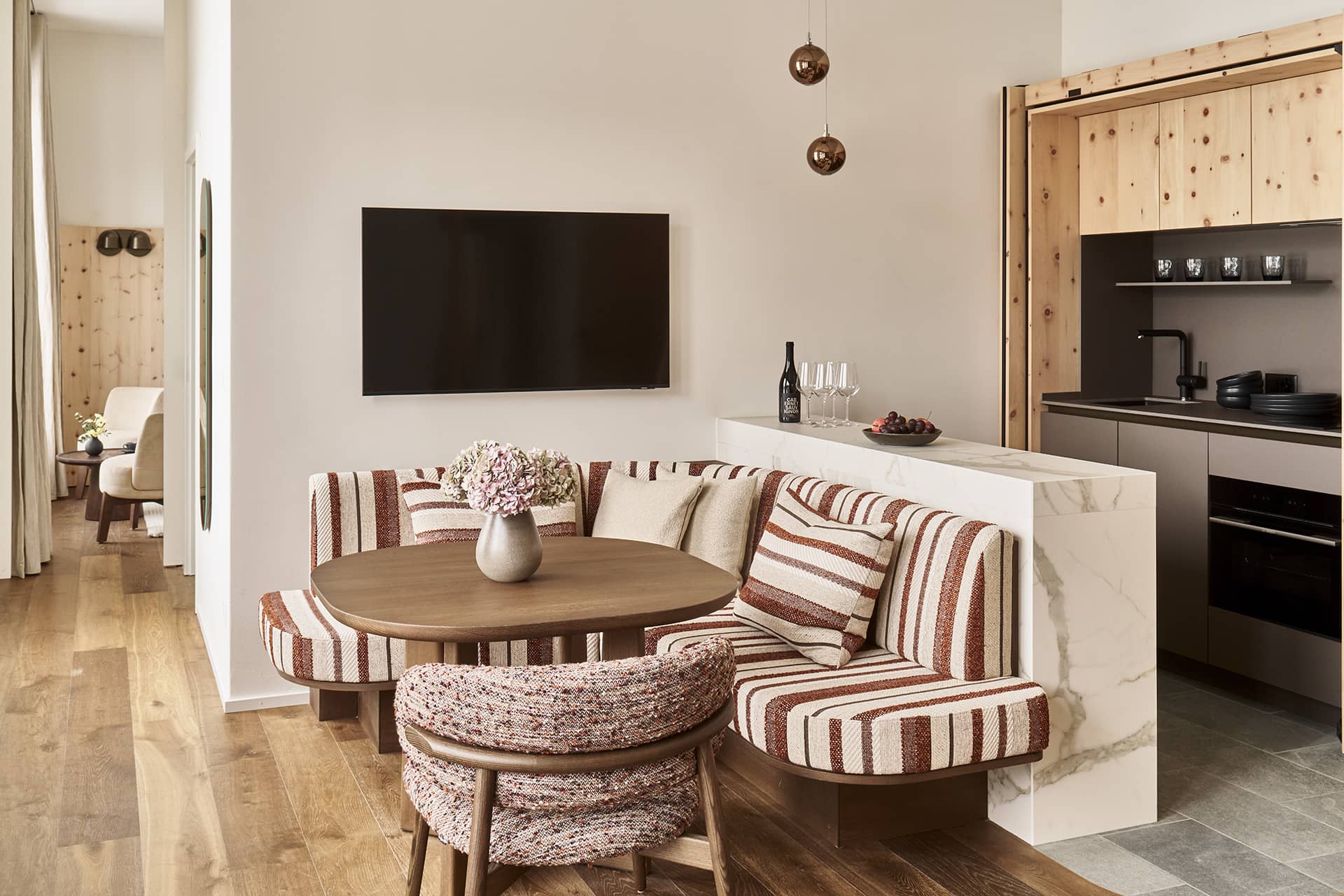 Essbereich mit gestreifter Sitzbank und angrenzender offener Küche im Masterpenthouse in St. Moritz